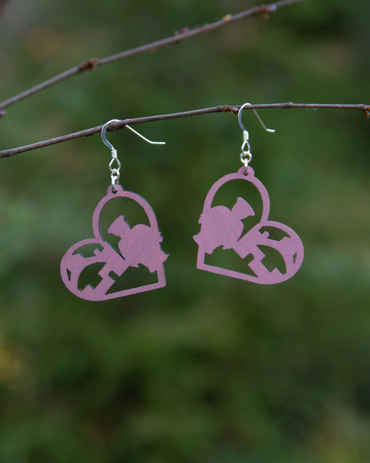Vaaleanpunaisen sävyiset Oulu-aiheiset korvakorut Oulu LOVE -korumallistosta. Korut ovat maalattua koivuvaneria ja niissä on hopeiset koukut.