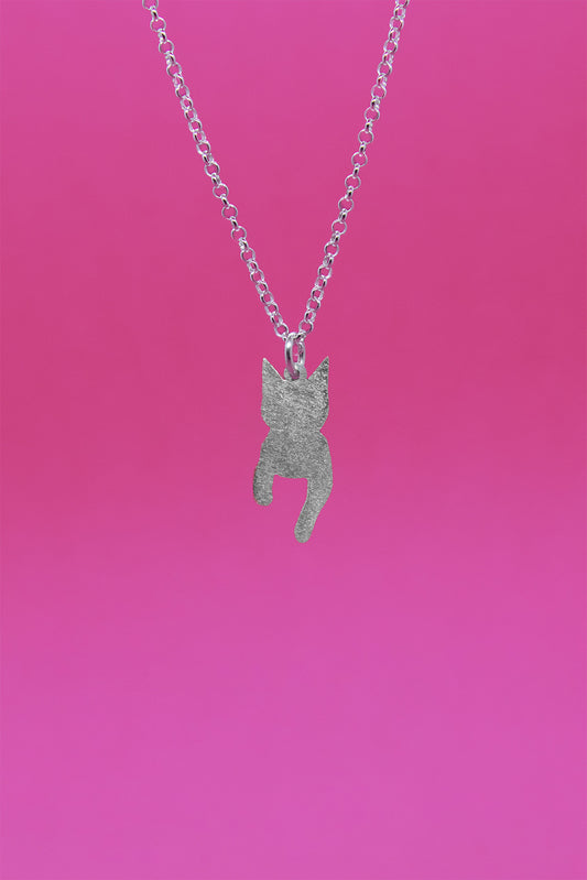 Hopeinen pieni ja mattapintainen kissaa esittävä riipus hopeaketjussa. Lähikuva riipuksesta.