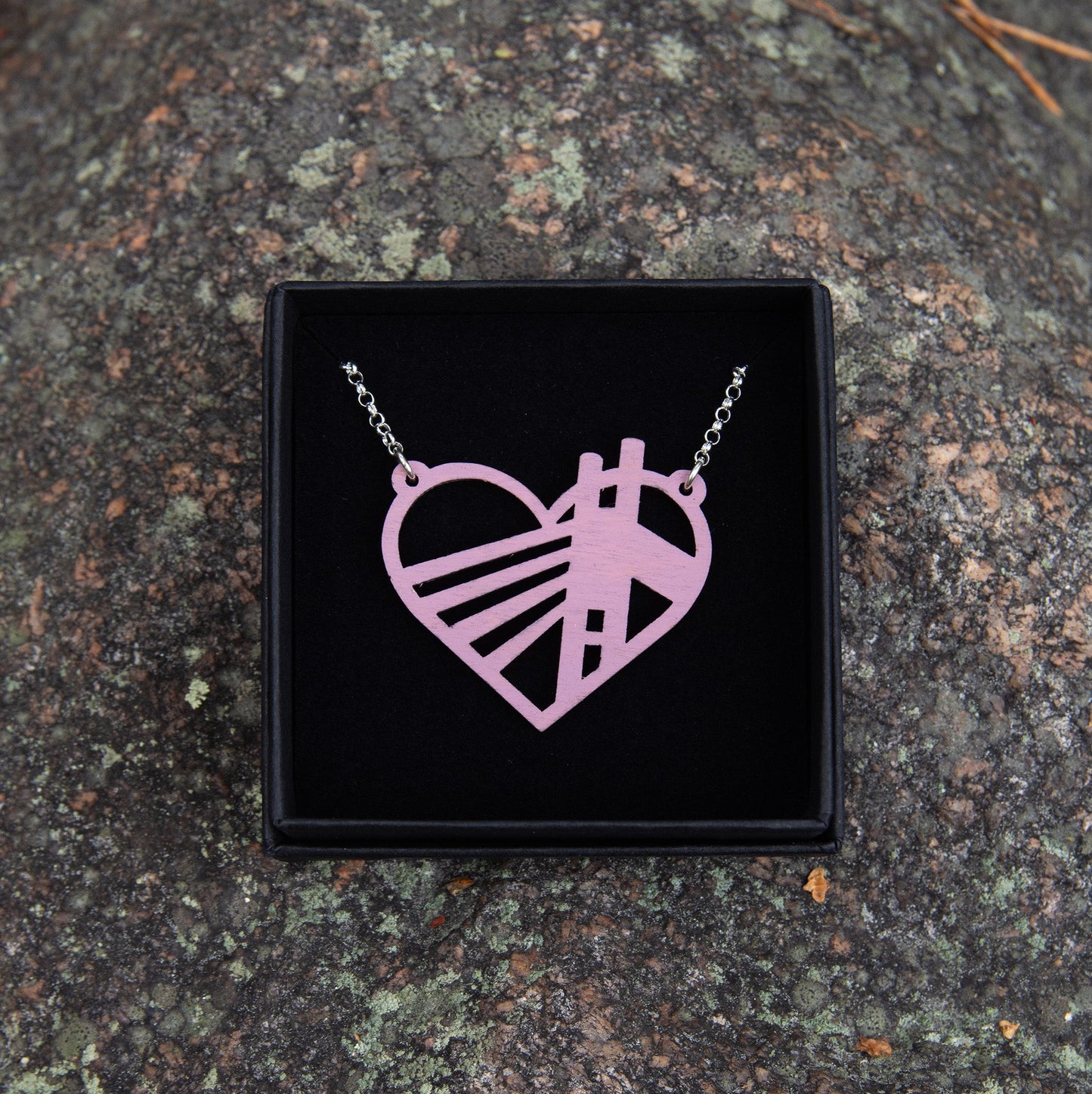 Vaaleanpunaisen sävyinen Jätkänkynttilä-sillasta muistuttava vanerikaulakoru. Korun kehämuoto muistuttaa sydäntä.