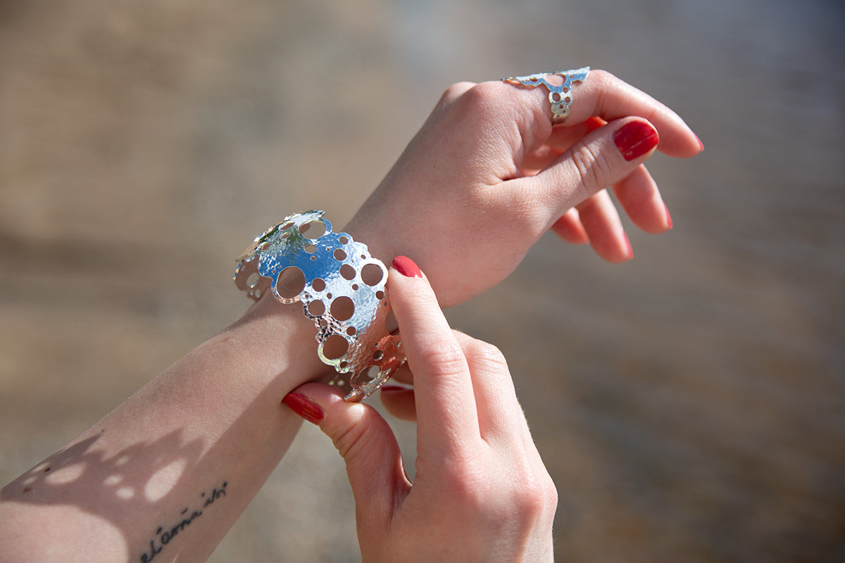 Malli pukee hopeista Rannalla-rannekorua vasempaan käteensä.