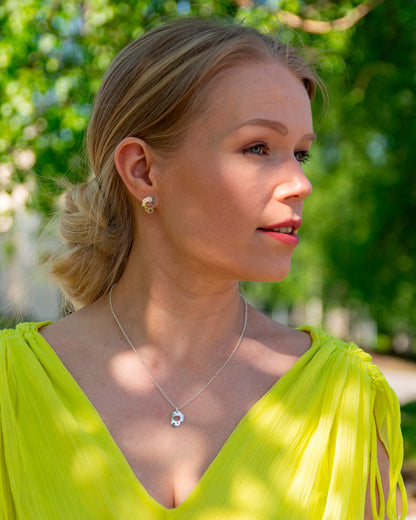 Naismallilla yllä sievät kiiltävät hopeakorvakorut, joissa on vasaroitu pinta, ilmava muotoilu ja epäsäännöllinen ulkokehä.
